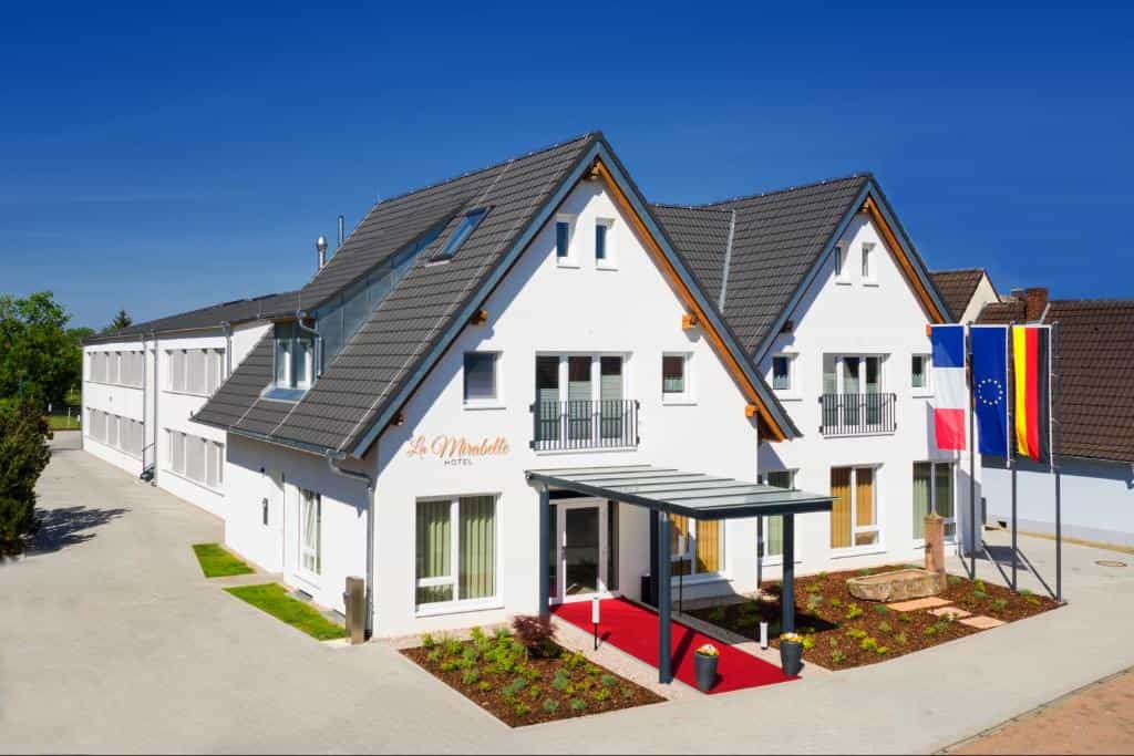 Hotel La Mirabelle in Ettenheim with French and German flags under a clear blue sky.