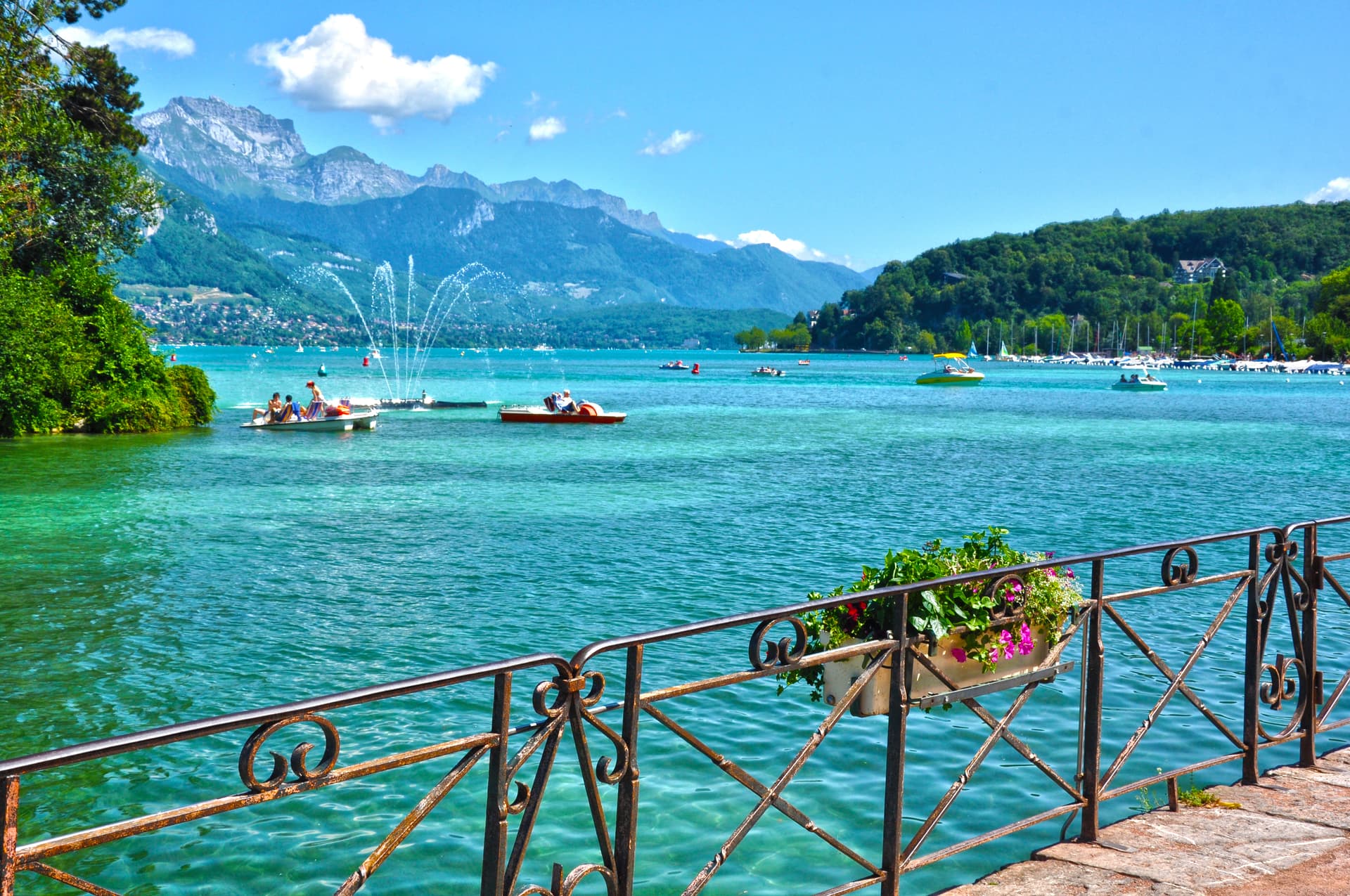 Boats on turquoise Lake Annecy with mountains in Haute-Savoie, France