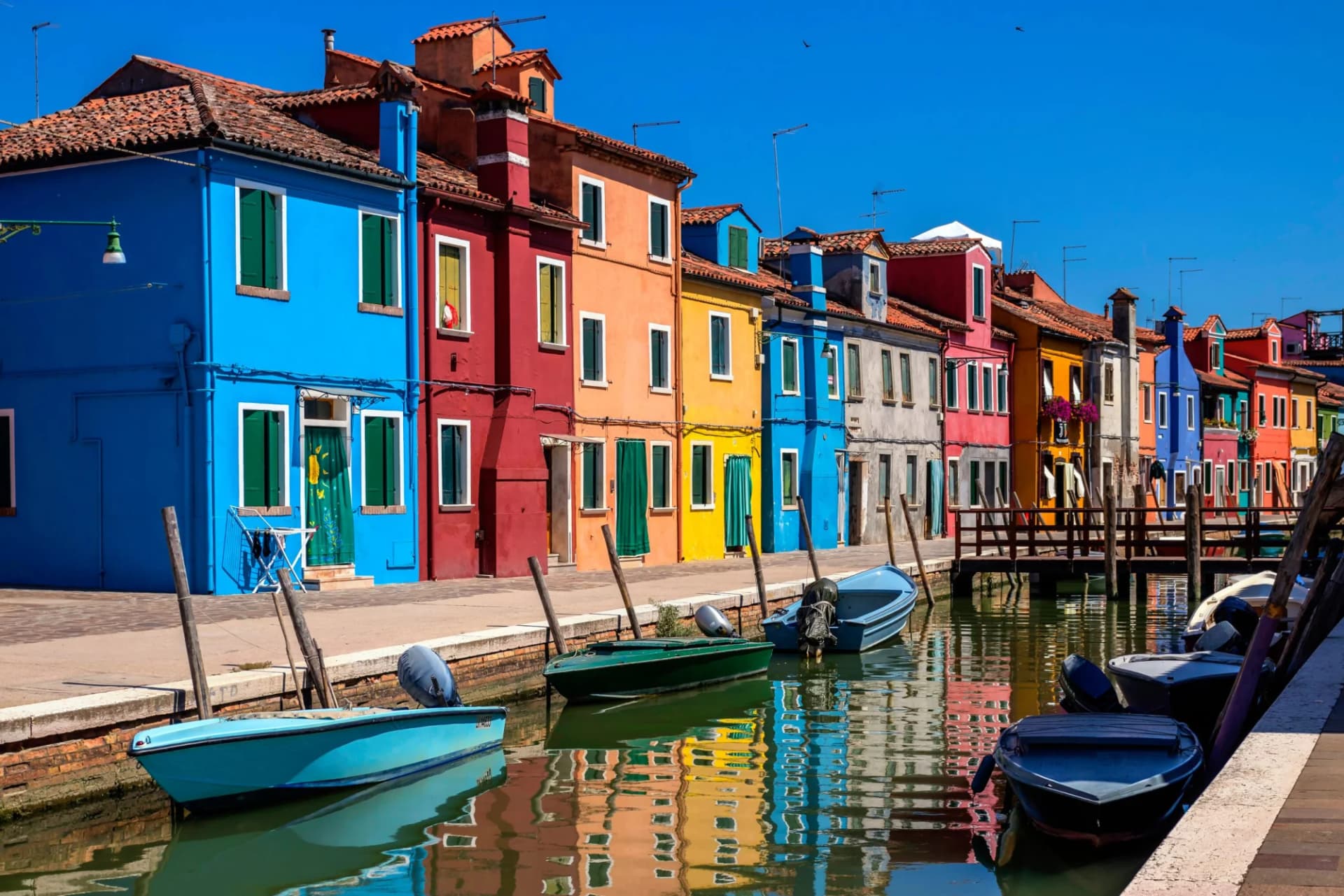 Colorful houses line a canal with moored boats reflecting in the water, Porto Vecchio.