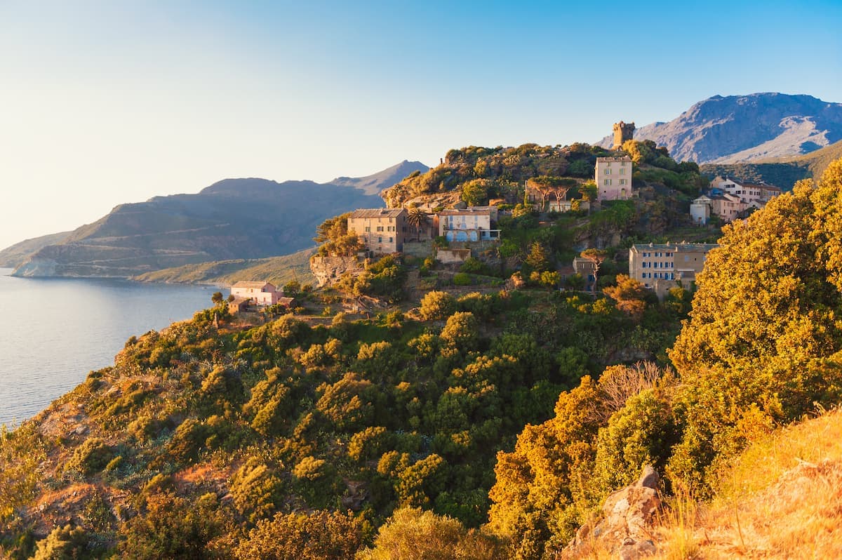 Hillside village with houses overlooking the sea and mountains in Corsica.