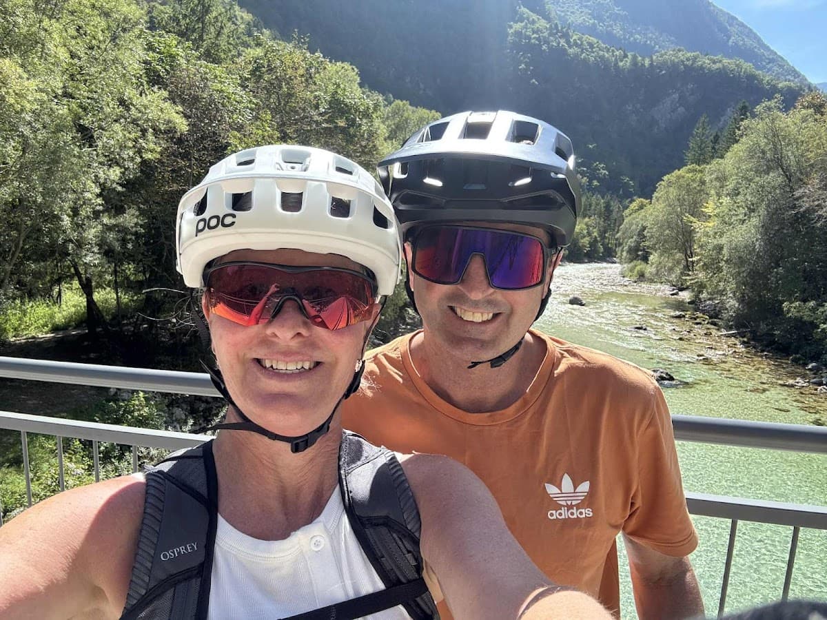Mountain bikers taking a selfie on a bridge over a clear green river valley