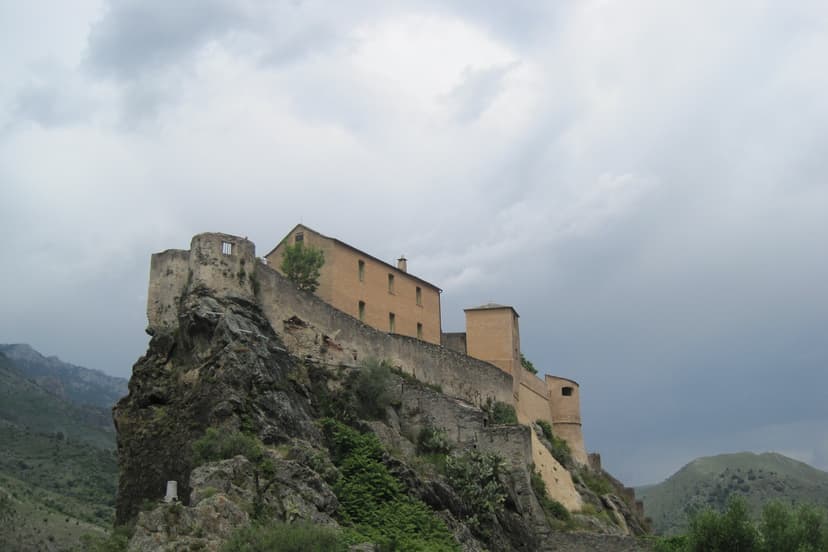 Historic stone fortress perched on a rocky cliff under a cloudy sky