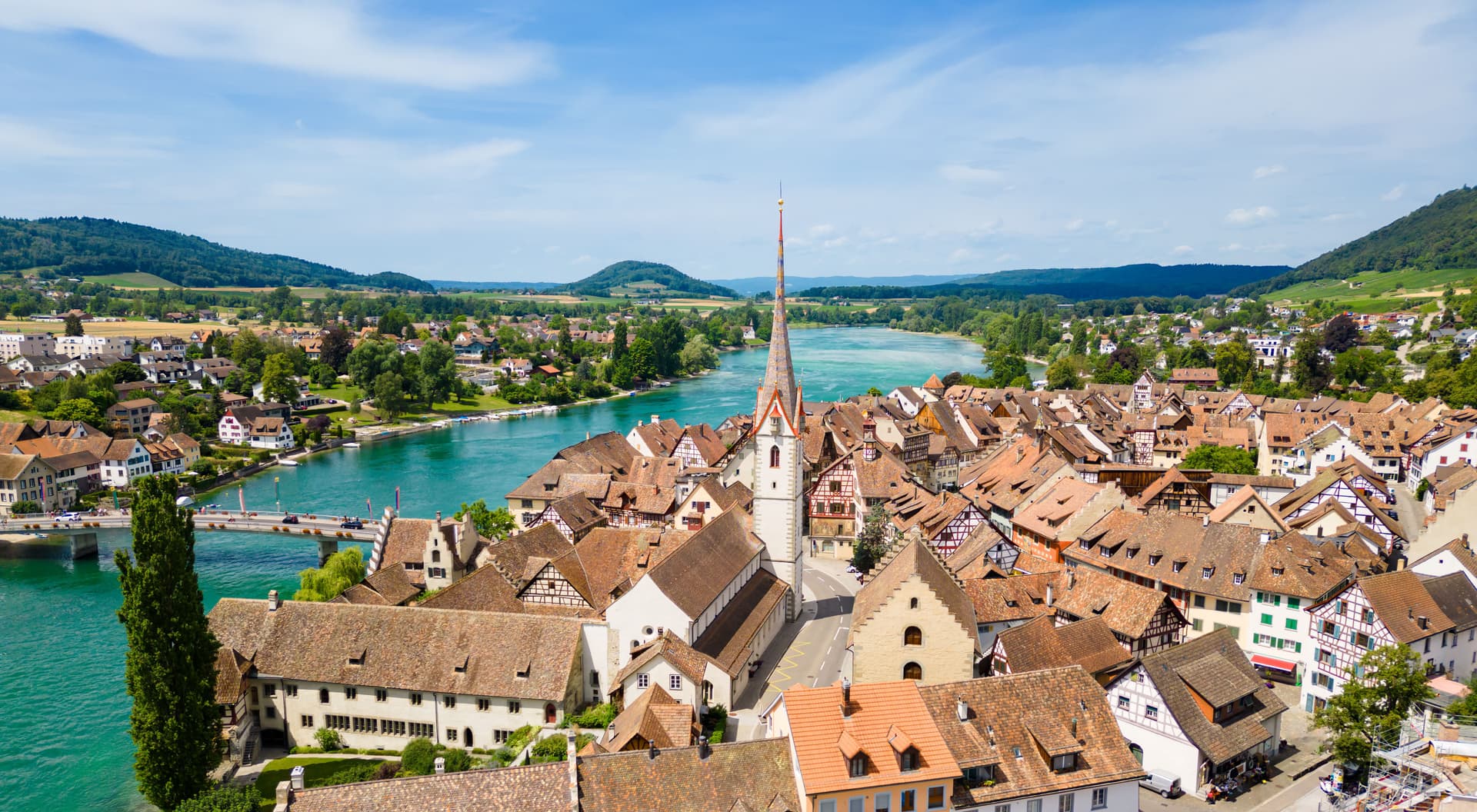 Aerial view of Stein am Rhein with terracotta roofs, a church spire, and the turquoise Rhine River.