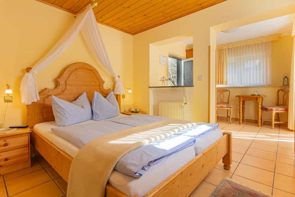 Bright hotel room with wooden bed, canopy, and yellow walls in Cochem.