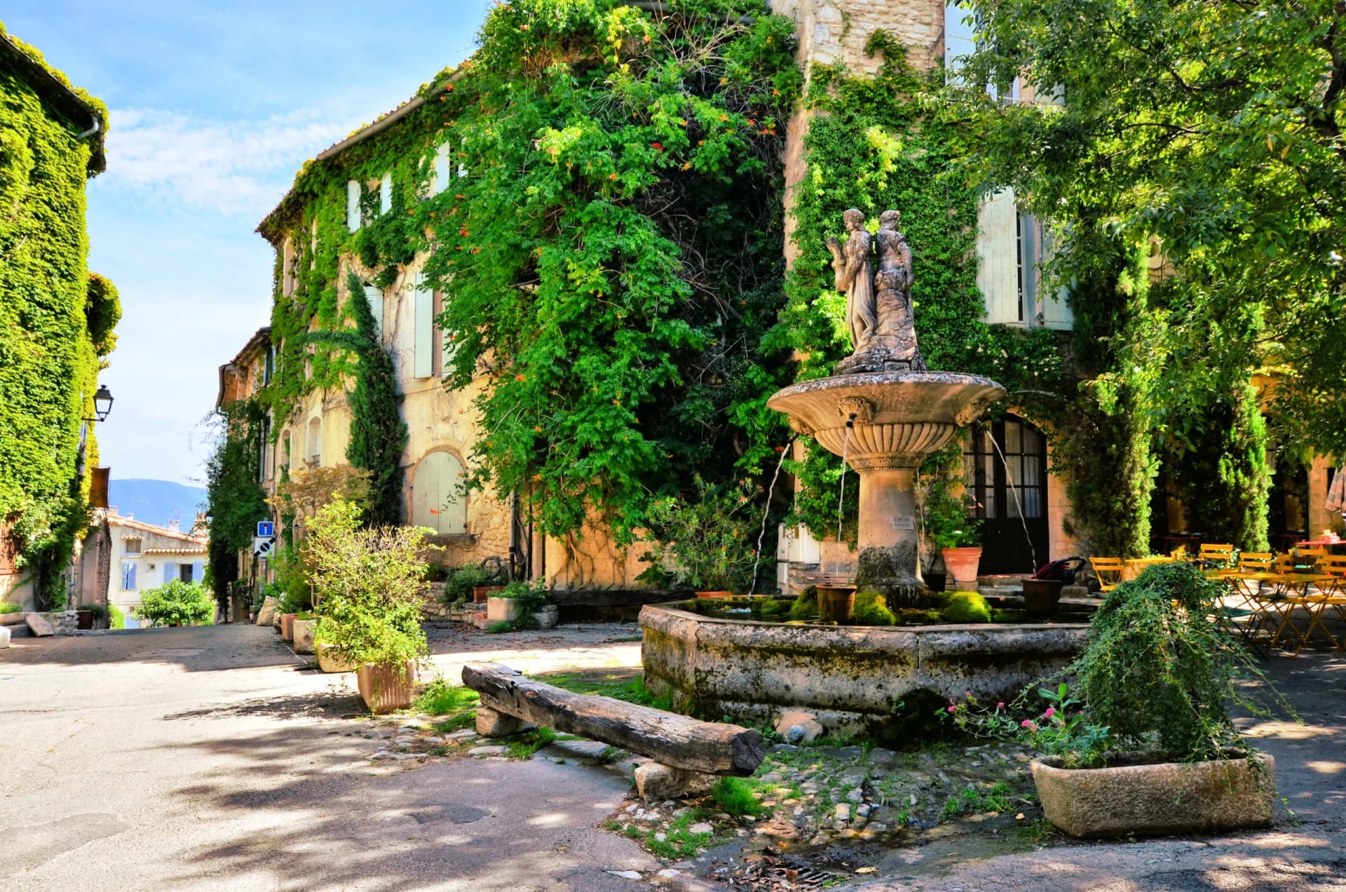 Leafy town square with mossy fountain statue in a picturesque village in Provence, France