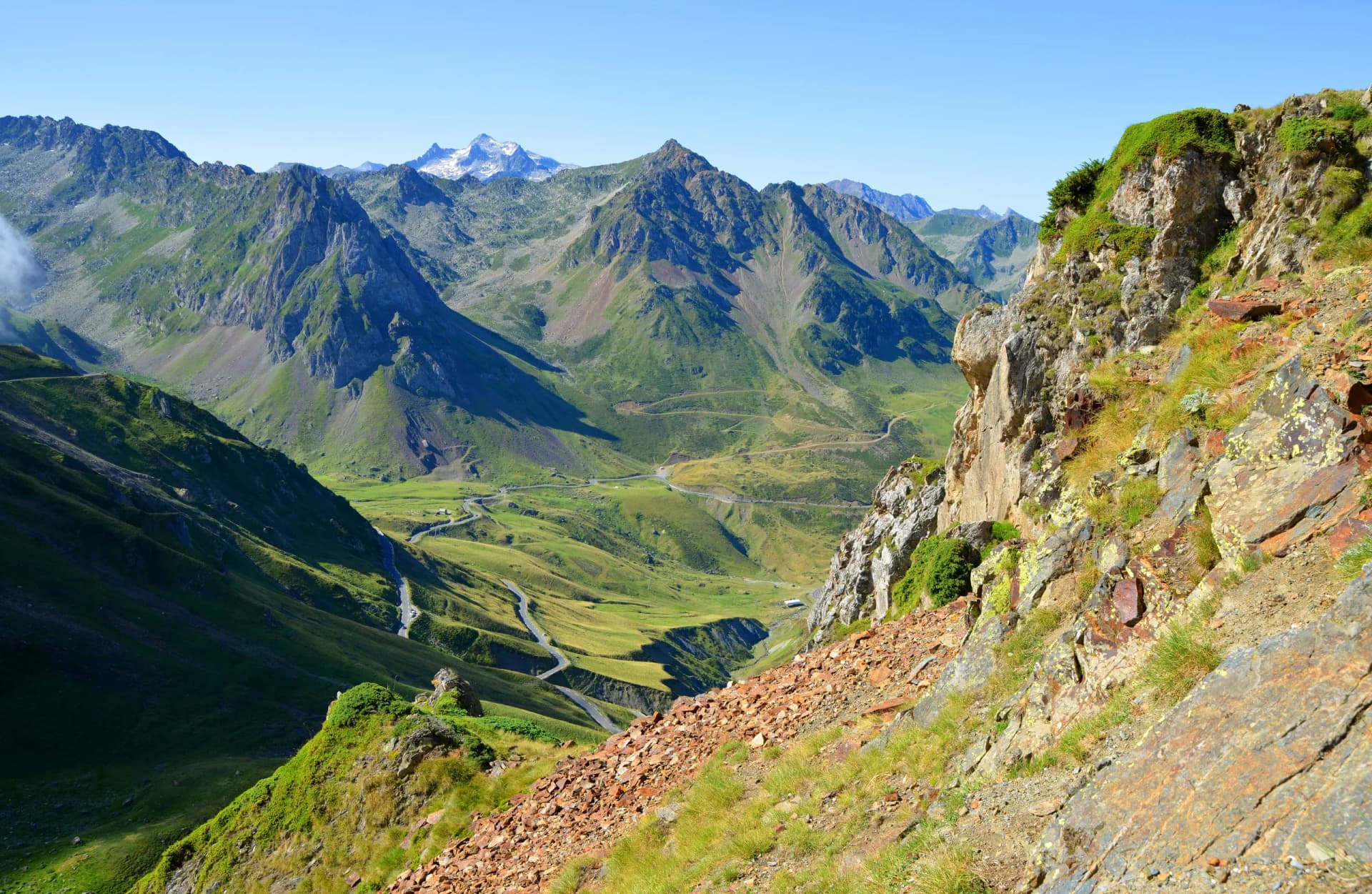 Winding mountain road through green valley at Col du Tourmalet in Pyrenees mountains, France