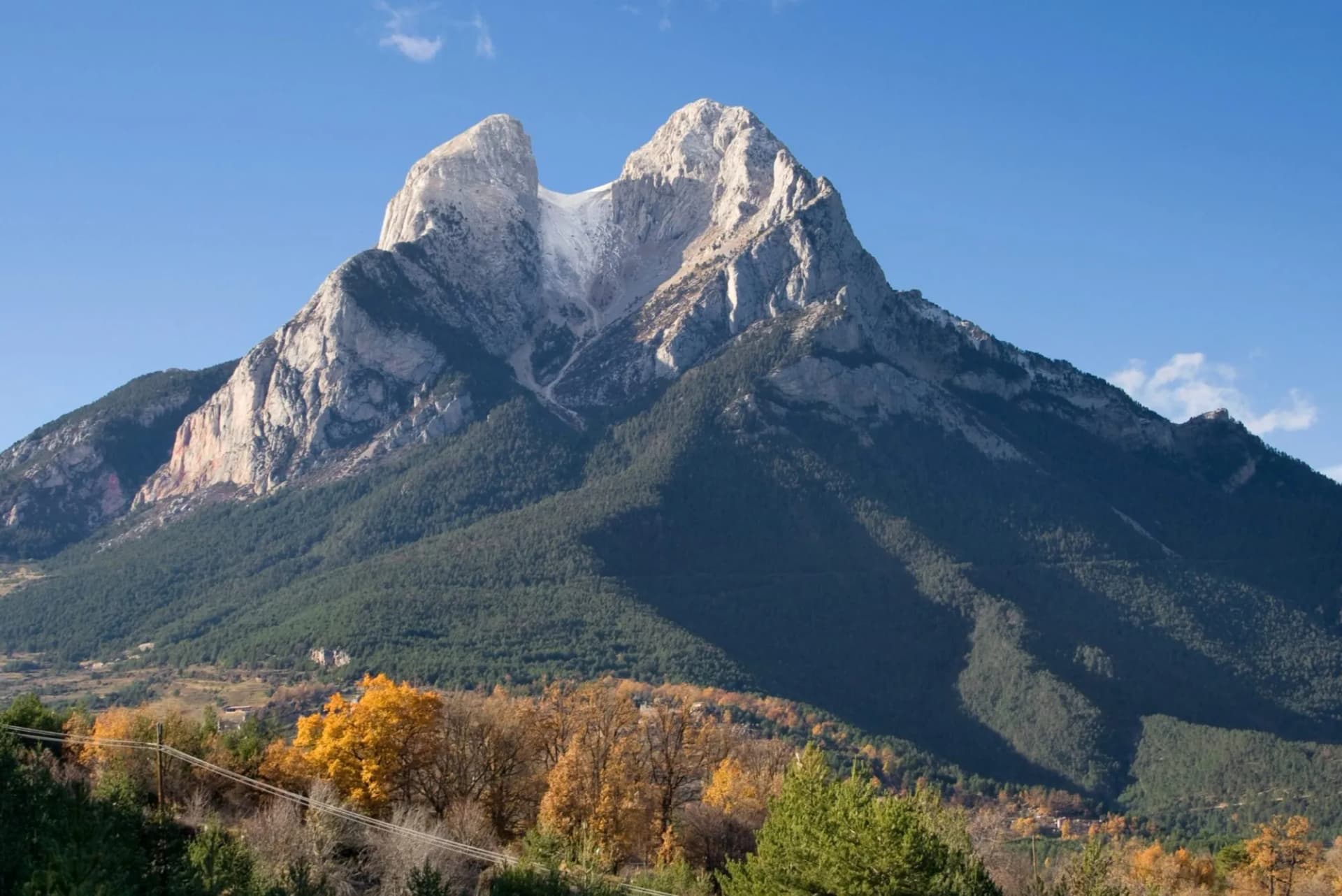 Pedraforca mountain in Catalonia, Spain, with forested slopes and autumn foliage.