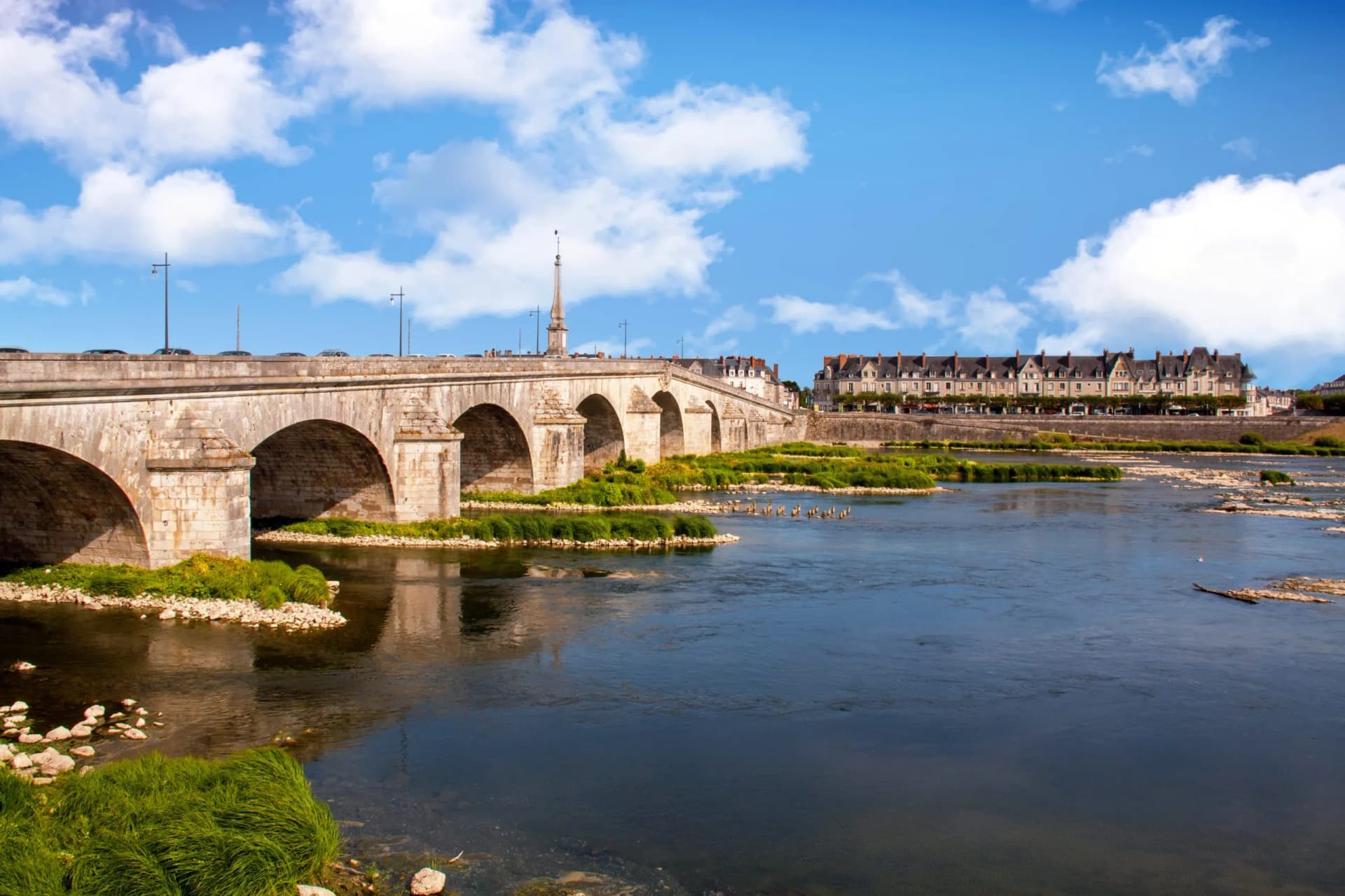Stone arch bridge built in the eighteenth century over a river with buildings in the background.