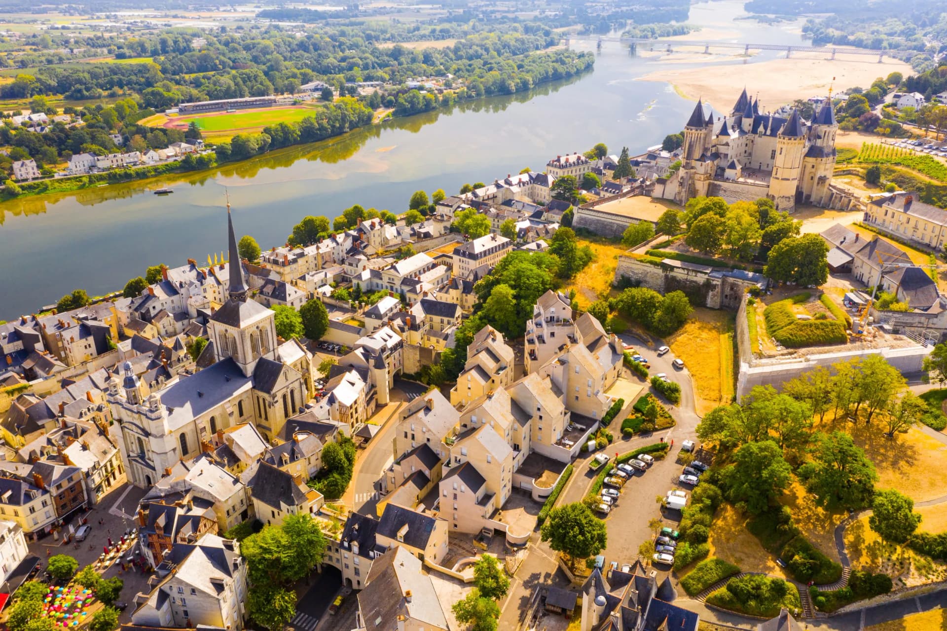 Aerial view of Saumur city, castle, and Loire River in France with church spire.