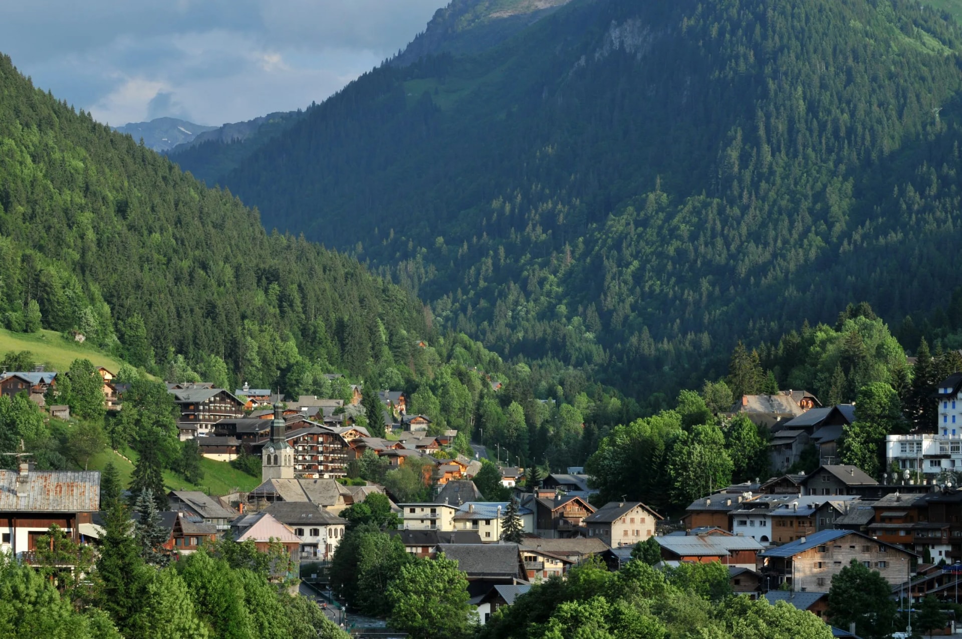 Alpine village of Morzine in Haute-Savoie nestled in steep, green, forested mountains.