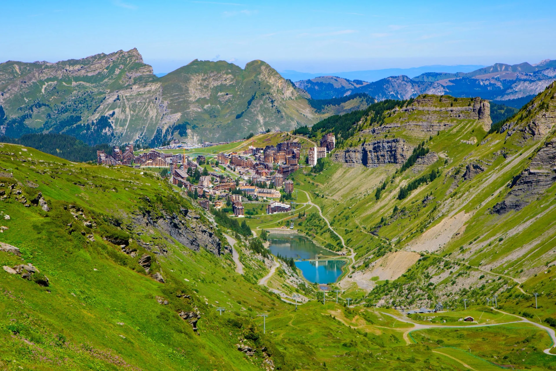 Avoriaz mountain resort in summer with green slopes, a small lake, and surrounding Alps in France.