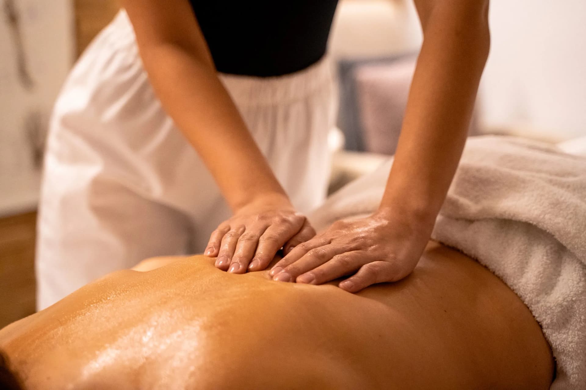 Close-up of oil massage therapy on a person's back with a therapist's hands applying pressure.