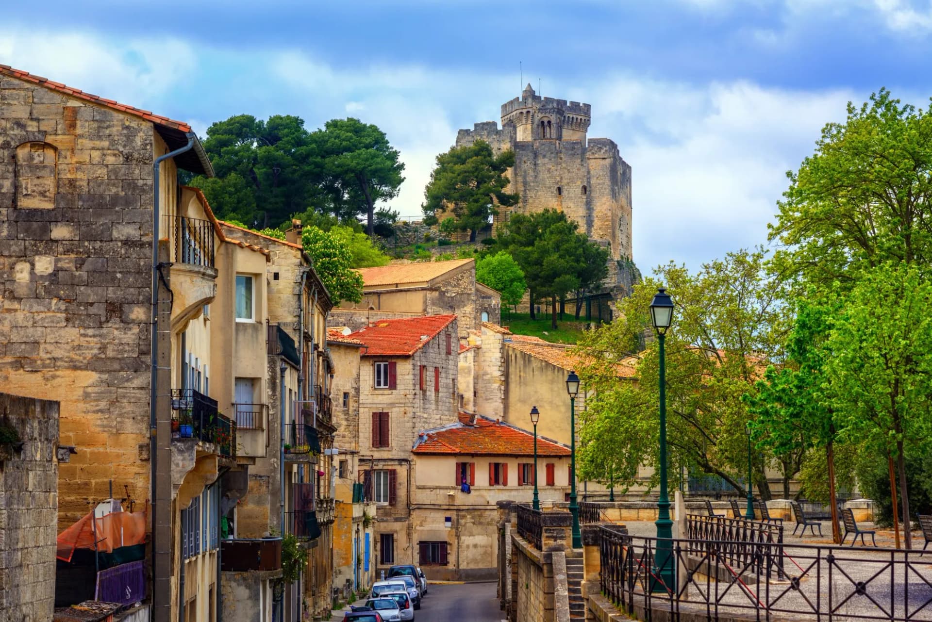 Historic stone buildings and a medieval castle overlooking a street in Beaucaire old town.