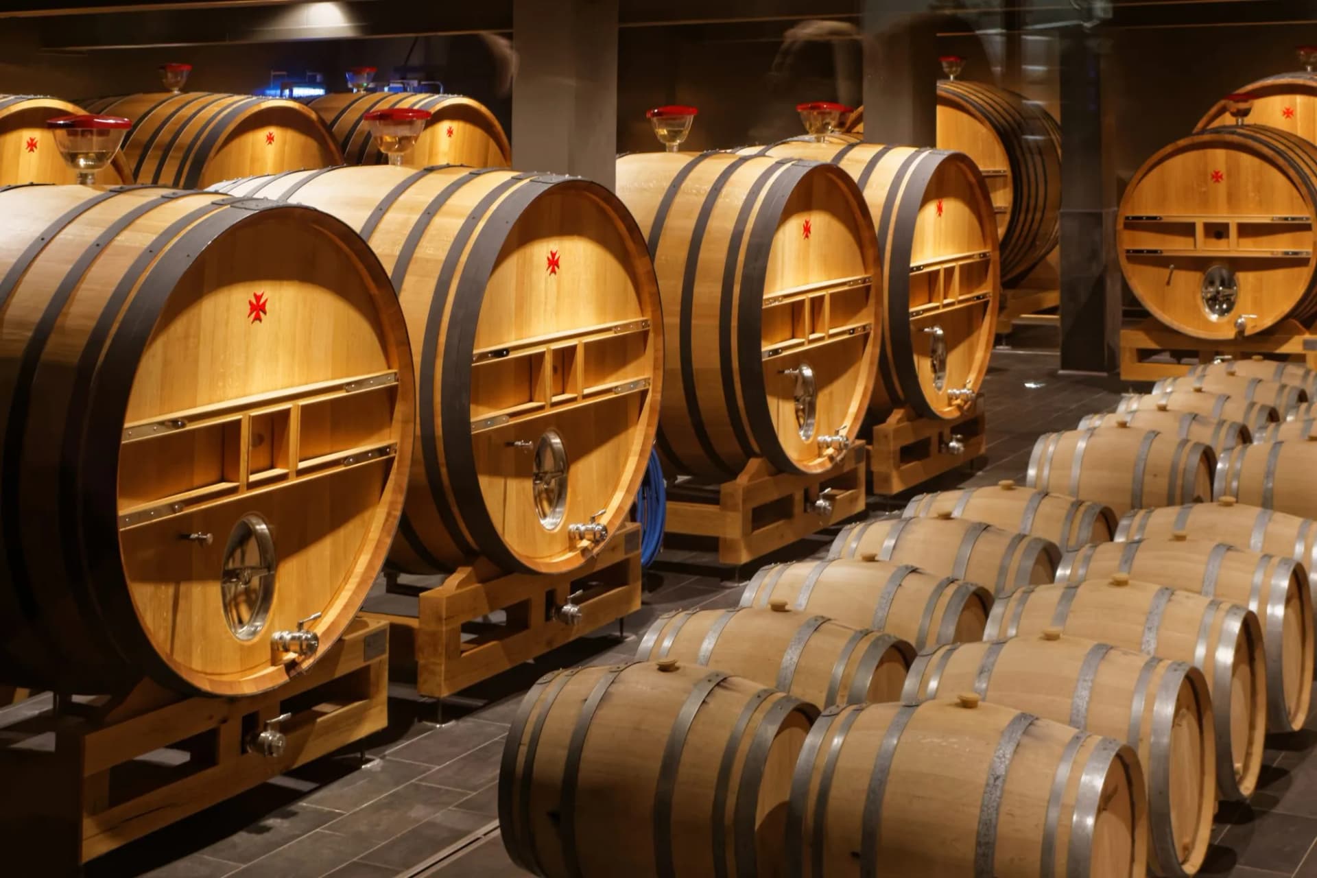 Wooden wine barrels aging in a dimly lit cellar in Reims, France.