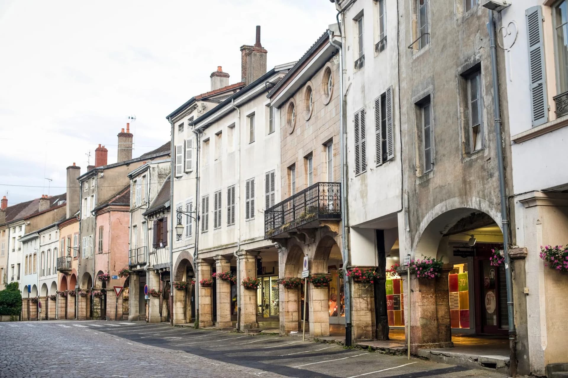 Historic street in Louhans with arcades and cobblestones under an overcast sky