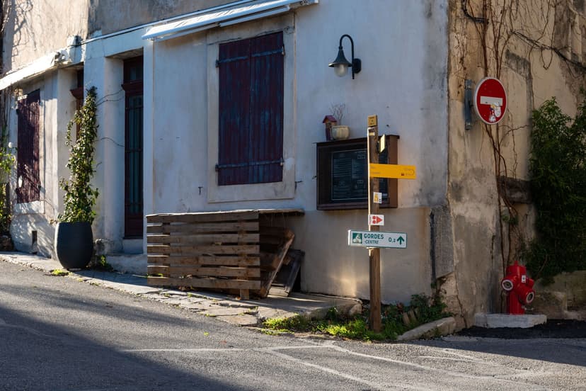 Stone building in Gordes with wooden shutters, signage, and street corner view