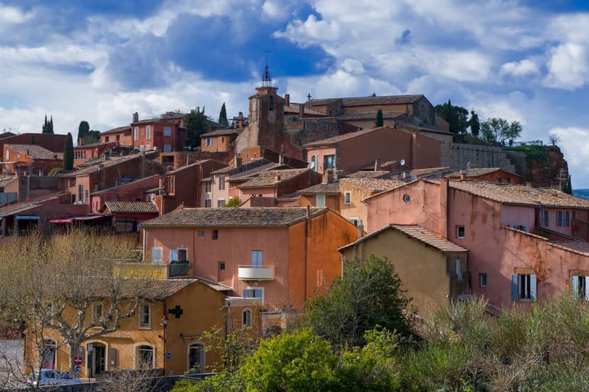 Roussillon ochre village with red and orange historic houses under a cloudy blue sky