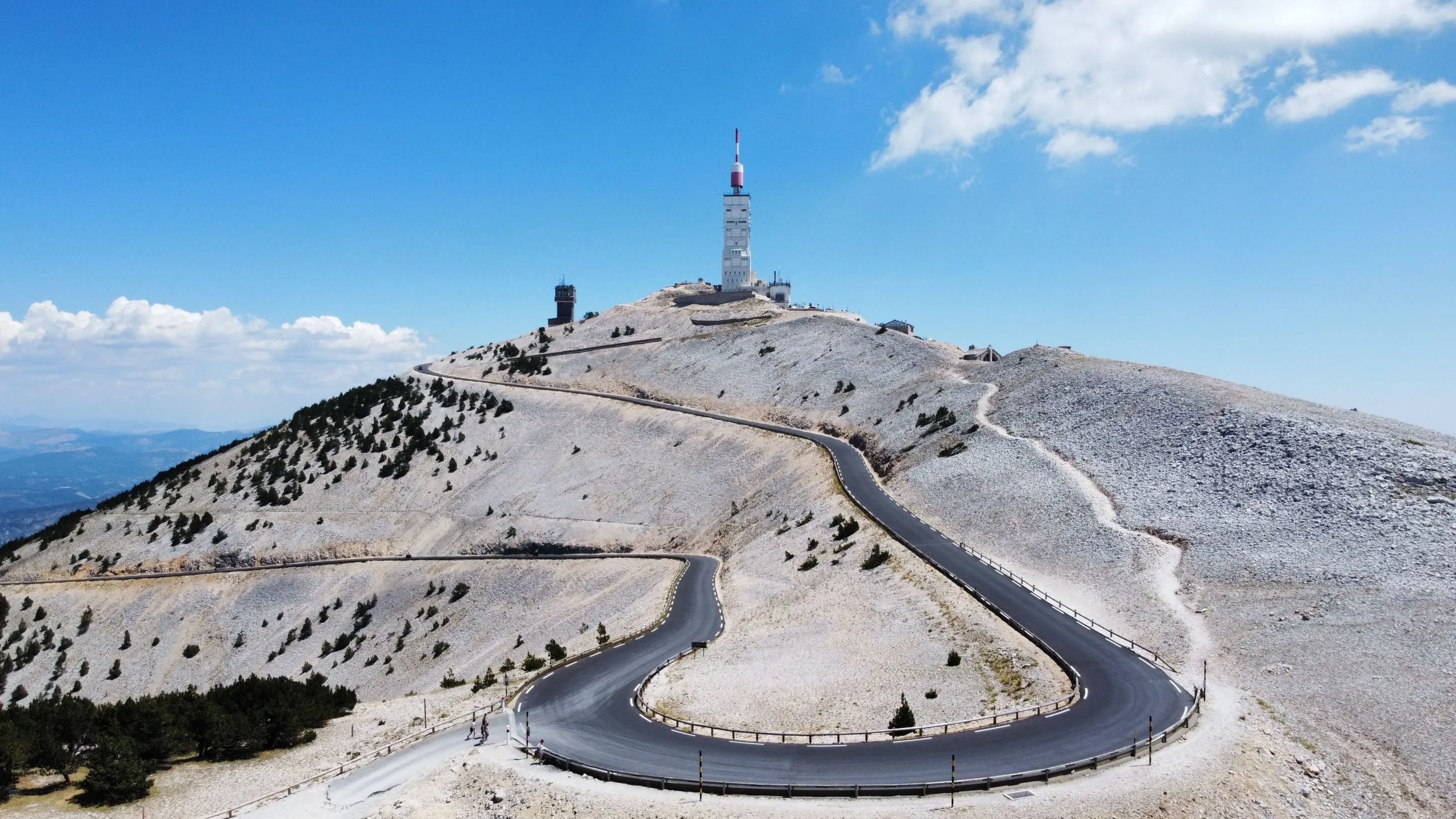 A narrow highway leading to the Mont Ventoux in France with a blue sky in the background