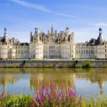 "Chambord, Frankrig - 31. juli 2009: Flot panoramabillede af slottet Chambord, der spejler sig i kanalen på en sommerdag med blå himmel. Der er nogle uigenkendelige mennesker på balkonerne"