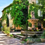 Grønt bytorv med springvand i en malerisk landsby i Provence, Frankrig